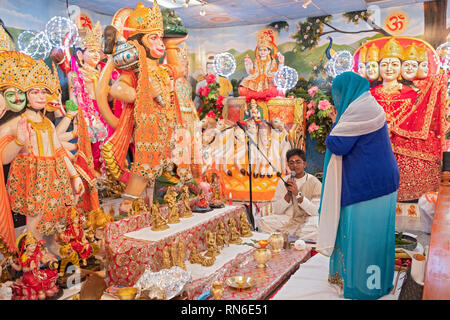 Ein frommer Hindu Frau feiert ihren 70. Geburtstag durch die Unterstützung der Service vor Statuen von Gottheiten, die betet. Stockfoto