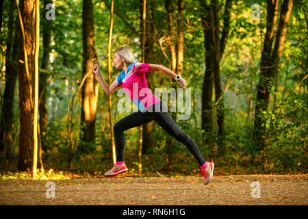 Foto von der Seite der Sport Frau läuft durch den Park unter Bäumen auf Sommer. Stockfoto