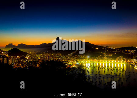 Rio de Janeiro Stadt Ansicht von oben mit der Corcovado (Christus der Reedeemer) Pedra da Gavea und Enseada de Botafogo, Brasilien vom Zuckerhut. Sonnenuntergang mit Stockfoto