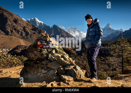 Nepal, Everest Base Camp Trek, Khumjung, Senior männliche Touristen Gebetsfahnen zu grobe Cairn von Steinen auf dem Weg gebunden Stockfoto