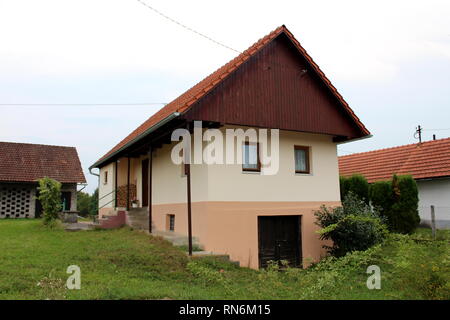 Renovierte kleine suburban Family House mit neuer Fassade und Dachziegel teilweise aus Holz mit großen Keller mit Gras umgeben sind Stockfoto
