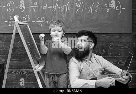Kid ein Gedicht, während Lehrer aufmerksam zuhört. Cooler Kerl in rosa Shirt sitzen auf dem Boden neben der ständigen Kid. Zurück zur Schule Stockfoto