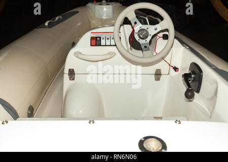 Eine Nahaufnahme des Lenkrads von einem kleinen weißen Gummi Motorboot mit Cockpit und Tasten auf der Instrumententafel Stockfoto