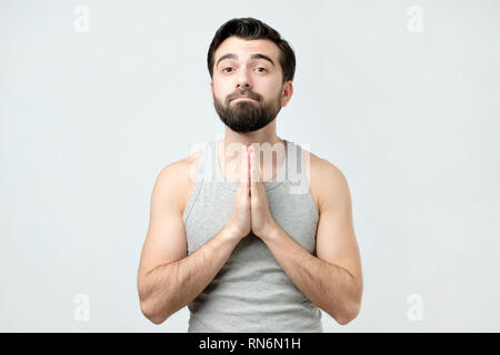 Verzweifelten jungen Mann mit gefalteten Händen, um Hilfe zu bitten. Stockfoto