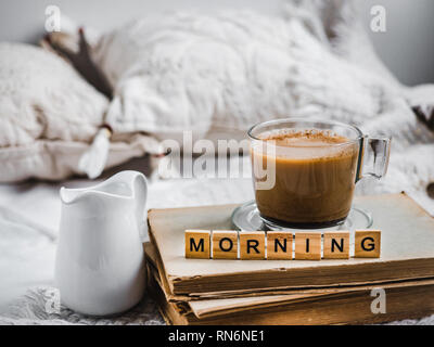 Tasse aromatischen Kaffee, Creamer mit frischer Milch, alte Bücher, Kissen und eine karierte. Frühstück in den frühen, sonnigen Morgen Stockfoto