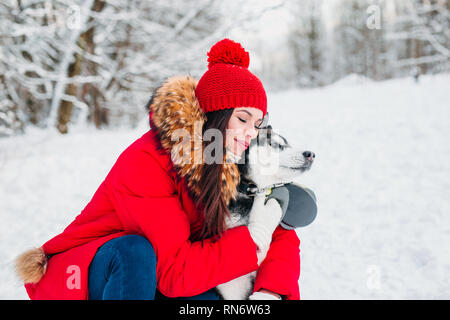 Frau streichelt die Husky Hund im Winter Wald Stockfoto