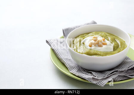 Grüne Suppe mit Pinienkerne in einer weißen Schüssel auf einem grauen Hintergrund close-up Stockfoto
