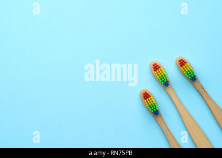 Foto von drei Holz- Zahnbürsten mit regenbogenfarbenen Borsten. Stockfoto