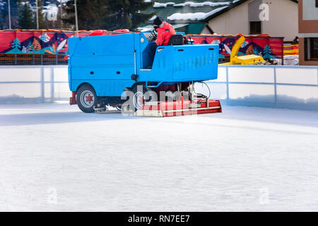 Ein Arbeiter schießt eine besondere Eis maintenant Maschine beim Sport Eisbahn. Kochmöglichkeit für Skating. Eis Zubereitung bei der Eisbahn zwischen den Sitzungen in der Stockfoto