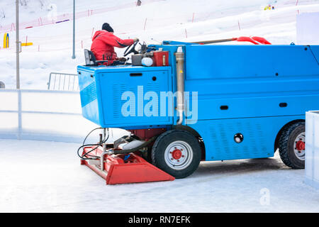 Ein Arbeiter schießt eine besondere Eis maintenant Maschine beim Sport Eisbahn. Kochmöglichkeit für Skating. Eis Zubereitung bei der Eisbahn zwischen den Sitzungen in der Stockfoto