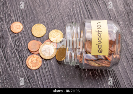 Glas Glas mit Münzen und Banknoten mit den Worten BILDUNG. Alte schwarz-Tabelle. Das Konzept der Einsparungen für den Unterricht an der Universität, Hochschule oder Col Stockfoto