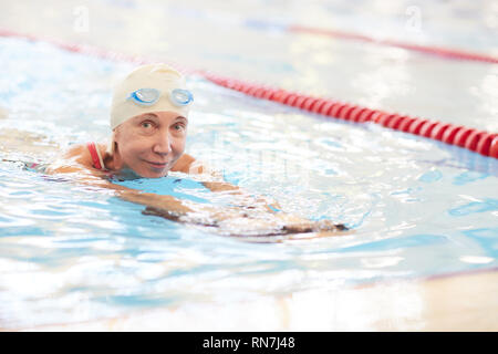 Lächelnd Senior Frau Schwimmen im Pool Stockfoto