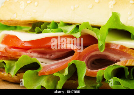 Nahaufnahme einer frischen knusprigen Baguette deli Sandwich. Sandwich mit Treffen, Speck, Salat, Gemüse, Salat, Tomaten, auf einer frischen in Scheiben Roggenbrot Stockfoto