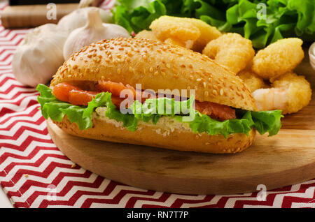 Sandwich mit Frischkäse, Lachs und Salat Öffnen auf einem Schneidebrett Stockfoto