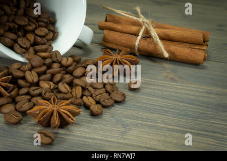 Geröstete Kaffeebohnen Verschütten von einer Schale, Zimt mit Sternanis Gewürz auf einem rustikalen Holztisch in der Nähe zu sehen. Stockfoto