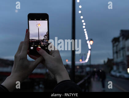 Mädchen nehmen Bild auf Ihrem iphone schöne Laterne in Whitby. Stockfoto