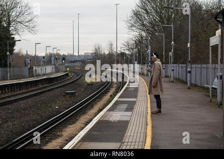 Mann zu sein Telefon suchen Zeit mit Warten auf den Zug zu töten. Stockfoto