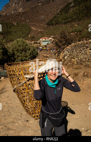 Nepal, Namche Bazar, Tourismus, ältere weibliche Touristen, Sherpa Korb mit tumpline Stirn Gurt Stockfoto