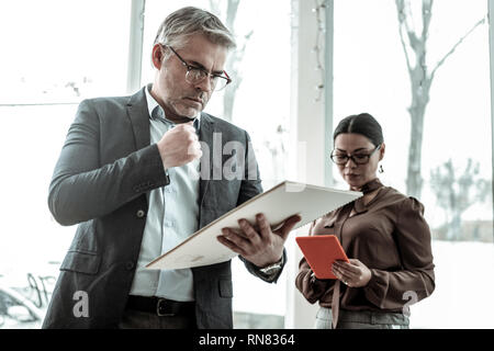 Hohe grauhaarige nach schöner Mann in Brillen suchen ernsthafte Stockfoto