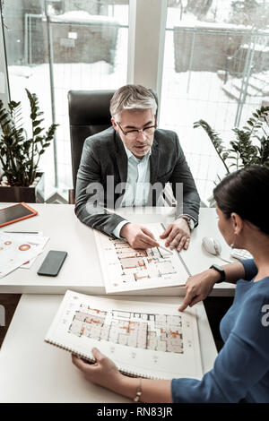 Grauhaarige ernster Mann in Brillen Diskussion der Projektdetails mit seinem Kollegen Stockfoto