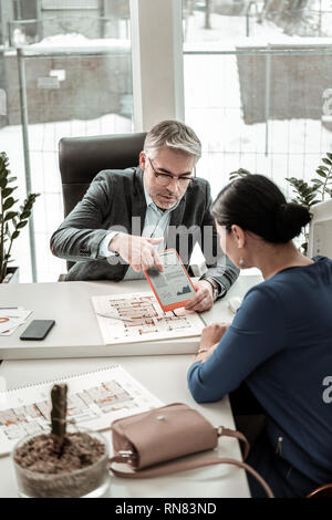 Grauhaarige ernster Mann in Brillen Teilen von Informationen mit seinem Kollegen Stockfoto