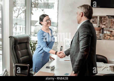 Dunkelhaarige schöne asiatische Frau in einem blauen Hemd positiv Stockfoto