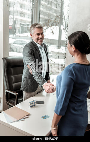 Hohe grauhaarige stattlicher Mann in Brillen Sitzung ein neuer Mitarbeiter Stockfoto