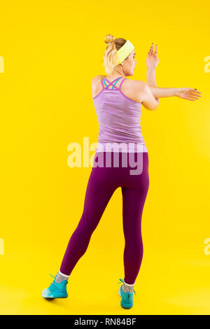 Schlanke Frau mit lila Leggings ihre Arme Stretching Stockfoto
