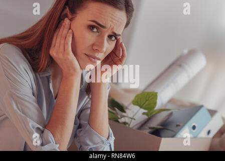 Arbeitslose Frau. Porträt der jungen distressed Arbeiter ihre Tempel berühren und zum Ausdruck Trauer in ihren Augen nach einem Job entlassen wird Stockfoto