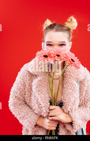 Blonde Frau mit schönen Frisur riechen Schöne Blumen Stockfoto