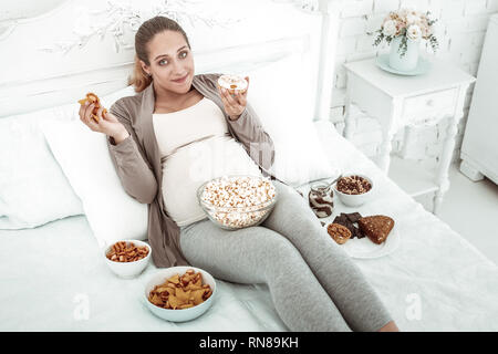 Angenehm Gute - Suche schwangere Frau in Bett im Junk Food abgedeckt Stockfoto