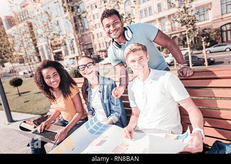 Außerhalb der Arbeit. Gruppe von Studenten das Lächeln auf den Gesichtern und in brechen, während gerade bei Camera suchen Stockfoto