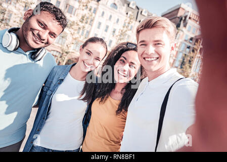 Posieren vor der Kamera. Attraktive männliche Person halten Lächeln auf seinem Gesicht und Stretching Hand, während bei Camera suchen Stockfoto