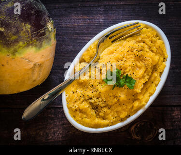 Gesundes Wurzelgemüse Schwede, mit einer Schüssel mit Schwede gekocht und in einer weißen Schüssel püriert. Dieses Gemüse ist in der Faser hoch. Stockfoto