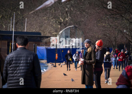 LONDON, UK, 21. März 2018: Die schöne blonde Mädchen Fütterung Vögel am Ufer des Sees im Hyde Park. Stockfoto