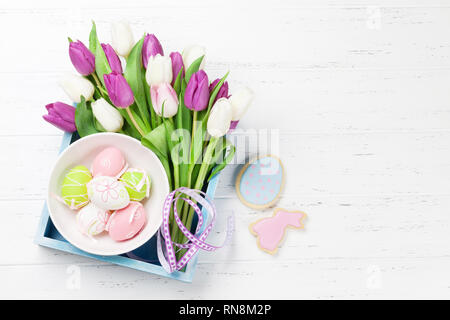 Ostern Grußkarte mit Tulpe Blumen Blumenstrauß und Ostereier. Draufsicht über weiße Holztisch mit Platz für Ihre Grußansagen Stockfoto