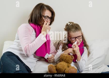 Kranke Mutter und Tochter. Eine Frau und ein Kind mit einer laufende Nase, Niesen, verwenden Sie ein Taschentuch. Stockfoto