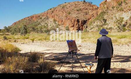 Ein Künstler Schritte zurück und betrachtet ihre Malerei der Glen Helen Schlucht in den west macdonnell Ranges in der Nähe von Alice Springs. Stockfoto