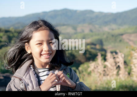 Asiatische Mädchen das Herz Form und lächelnd mit Reisen auf Berge und Sonnenlicht mit kopieren. Stockfoto