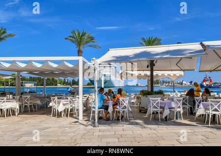 Touristen genießen a waterfront Nachmittag Mahlzeit auf dem Brindisi, Italien Promenade als großes Kreuzfahrtschiff bereitet sich auf Dock an einem Sommertag in Apulien. Stockfoto