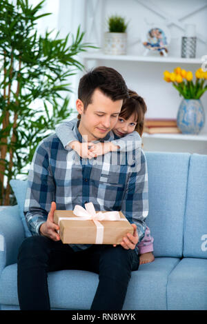 Süße kleine Mädchen, Tochter, Schwester umarmt Vater oder Bruder und gibt ihm ein Geschenk. Stockfoto