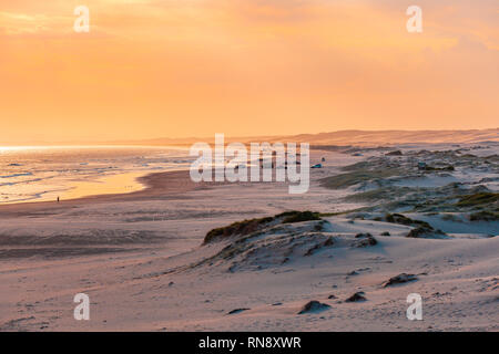 Autos am Strand parken direkt neben dem Wasser bei Sonnenuntergang in Australien Stockfoto