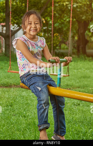 Asiatische Mädchen spielen auf einem teetertotter in einem Park. Filipina Kid. Stockfoto