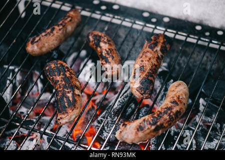 Selektiver Fokus von Gegrilltem verstreut leckere Wurst in Rauch auf bbq-Raster Stockfoto