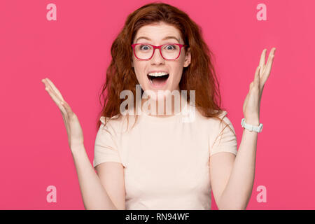 Happy rothaarige junge Frau Gefühl Sieger auf rosa Hintergrund isoliert Stockfoto