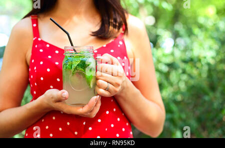 Junge brünette Frau mit einem marmeladenglas in ihrer Hand mit einem Mojito. Sommer trinken Konzept Stockfoto