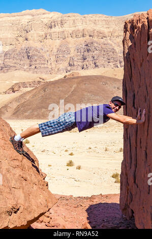 Eilat, Israel - 20. März 2017: Touristische, junger Mann horizontal Kletterte zwischen zwei Teilen der alten Zeit vor Split Rock in Timna Nationalpark in Isra Stockfoto