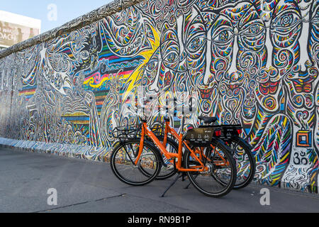 Berlin/Deutschland - vom 30. Juni 2018: Orange Dock - weniger Fahrräder mieten an der East Side Gallery, einem 1316 m langen Überbleibsel der Berliner Mauer gemalt mit Graffiti Stockfoto