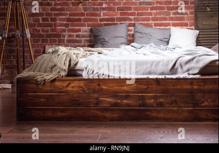 Stilvolles Interieur - Holzbett und die Rote Wand aus Stein Stockfoto