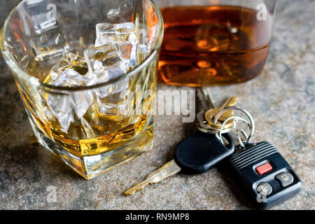 Nahaufnahme von Brandy Glas mit Eis, Schlüssel und Flasche unscharf im Hintergrund. Schuss auf neutralem Hintergrund. Stockfoto